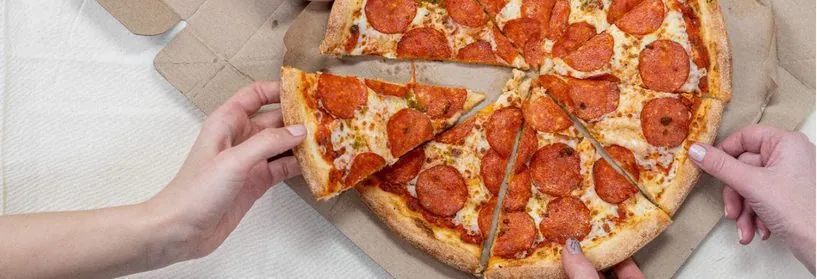 Hands reaching for slices of a delivery pepperoni pizza